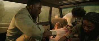 Movie still from “Beast” (2022), directed by Baltasar Kormákur – A man in the back of a car with a bandaged arm; Medium shot, High angle