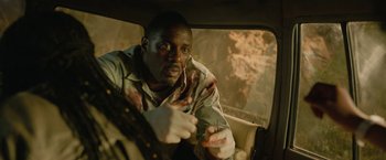 Movie still from “Beast” (2022), directed by Baltasar Kormákur – A man sitting in the back seat of a car; Close Up shot, High angle