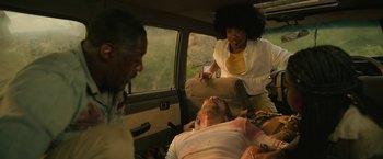 Movie still from “Beast” (2022), directed by Baltasar Kormákur – A woman standing next to a man in the back of a car; Medium shot, Over the shoulder angle
