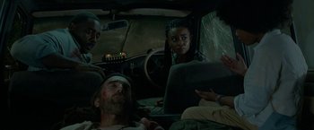 Movie still from “Beast” (2022), directed by Baltasar Kormákur – A group of people sitting in the back of a car; Medium shot, Low angle