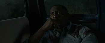 Movie still from “Beast” (2022), directed by Baltasar Kormákur – A man sitting in a car with his hand under his chin; Close Up shot, High angle