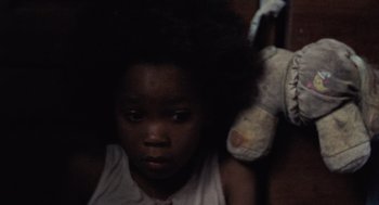 Movie still from “Beasts of the Southern Wild” (2012), directed by Benh Zeitlin – A young child with a stuffed animal in a dark room; Close Up shot, High angle