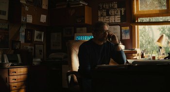 Movie still from “Beautiful Boy” (2018), directed by Felix van Groeningen – A man sitting at a desk talking on a phone; Medium shot, Low angle
