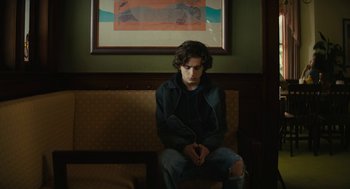 Movie still from “Beautiful Boy” (2018), directed by Felix van Groeningen – A man sitting on top of a bench in a room; Medium shot, Low angle