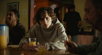 Movie still from “Beautiful Boy” (2018), directed by Felix van Groeningen – A person sitting at a table with a glass of orange juice; Medium shot, Over the shoulder angle