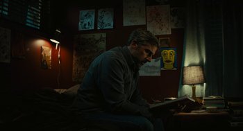 Movie still from “Beautiful Boy” (2018), directed by Felix van Groeningen – A man sitting on a couch looking at a laptop computer; Medium shot, Low angle
