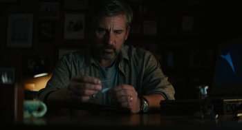 Movie still from “Beautiful Boy” (2018), directed by Felix van Groeningen – A man sitting at a wooden table holding a cell phone; Close Up shot, Low angle