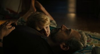 Movie still from “Beautiful Boy” (2018), directed by Felix van Groeningen – A man and a child laying on the floor; Close Up shot, High angle