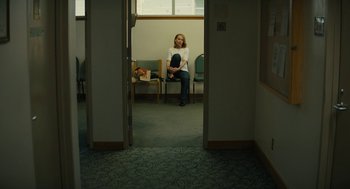 Movie still from “Beautiful Boy” (2018), directed by Felix van Groeningen – A woman sitting on a chair in a waiting room; Wide shot, High angle