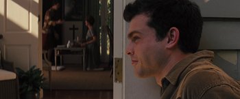 Movie still from “Beautiful Creatures” (2013), directed by Richard LaGravenese – A man looking out of a door while a woman stands in the background; Medium shot, Over the shoulder angle