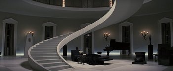 A living room with a grand piano and a spiral staircase