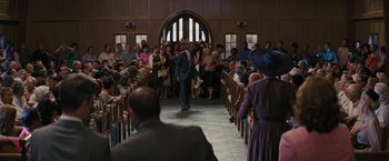 Movie still from “Beautiful Creatures” (2013), directed by Richard LaGravenese – A man walking down the aisle in front of a group of people; Wide shot, Low angle