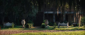 Movie still from “Beautiful Creatures” (2013), directed by Richard LaGravenese – A garden area with plants and a stone statue; Extreme Wide shot, High angle