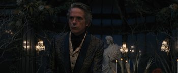 Movie still from “Beautiful Creatures” (2013), directed by Richard LaGravenese – A man wearing a suit and tie standing in front of a statue; Medium shot, Over the shoulder angle