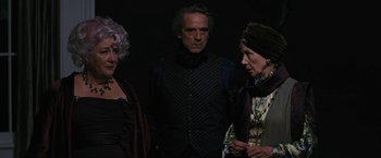 Movie still from “Beautiful Creatures” (2013), directed by Richard LaGravenese – A man and two women standing next to each other in front of a black background; Medium shot, Low angle