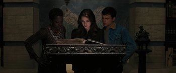 Movie still from “Beautiful Creatures” (2013), directed by Richard LaGravenese – A woman reading a book while two men look on; Medium shot, High angle