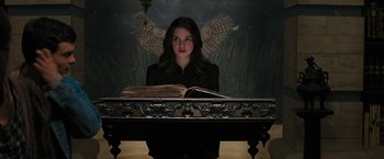 Movie still from “Beautiful Creatures” (2013), directed by Richard LaGravenese – A woman sitting in front of an open book on top of a table; Medium shot, Low angle
