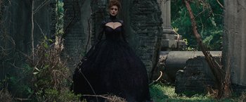 Movie still from “Beautiful Creatures” (2013), directed by Richard LaGravenese – A woman in a black dress standing next to a tree; Wide shot, Low angle