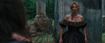 Movie still from “Beautiful Creatures” (2013), directed by Richard LaGravenese – A woman in a black and gold dress standing in front of a grave; Medium shot, Over the shoulder angle