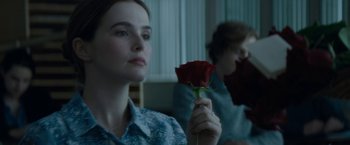 A woman holding a red rose in front of another woman