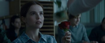 A woman holding a red rose in her hand