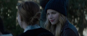 A woman wearing a hat is talking to another woman