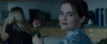 A woman holding a red rose in her hand