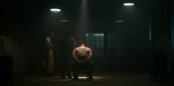 Movie still from “Fargo” (2014), created by Noah Hawley – A man sitting on a chair in a dark room; Wide shot, Low angle