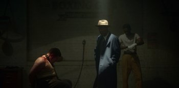 Movie still from “Fargo” (2014), created by Noah Hawley – A man wearing a hat standing next to two other men; Wide shot, High angle