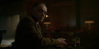 Movie still from “Fargo” (2014), created by Noah Hawley – A man sitting at a table in a dark room; Close Up shot, Low angle