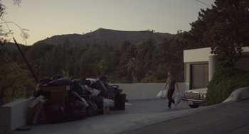Movie still from “Beginners” (2010), directed by Mike Mills – A man walking down a street with a bag of trash; Wide shot, Low angle