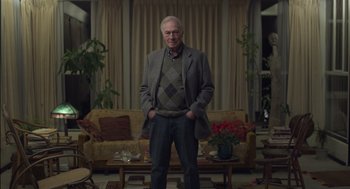 Movie still from “Beginners” (2010), directed by Mike Mills – An older man standing in front of a living room; Medium shot, Low angle