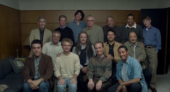 Movie still from “Beginners” (2010), directed by Mike Mills – A group of men sitting and standing in a room; Wide shot, High angle