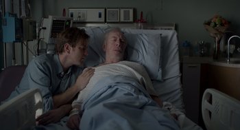 Movie still from “Beginners” (2010), directed by Mike Mills – A man in a hospital bed next to another man who is laying in bed; Medium shot, Over the shoulder angle