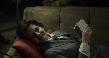 Movie still from “Beginners” (2010), directed by Mike Mills – A woman is laying on a couch and holding a notebook; Medium shot, High angle