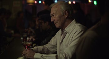 Movie still from “Beginners” (2010), directed by Mike Mills – An older man sitting at a table with a drink; Close Up shot, Over the shoulder angle
