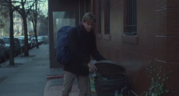 Movie still from “Beginners” (2010), directed by Mike Mills – A man with a blue backpack is loading a trash can; Medium shot, Low angle