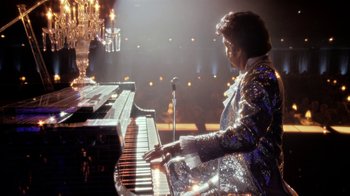 Movie still from “Behind the Candelabra” (2013), directed by Steven Soderbergh – A man in a sequined jacket playing the piano; Wide shot, Low angle