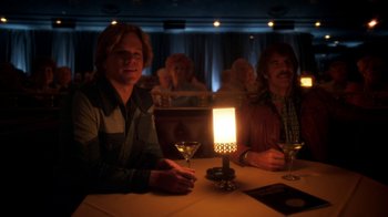 Movie still from “Behind the Candelabra” (2013), directed by Steven Soderbergh – Two men sitting at a table in front of a lit candle; Medium shot, Over the shoulder angle