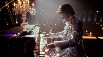 Movie still from “Behind the Candelabra” (2013), directed by Steven Soderbergh – A man in a sequined jacket playing a piano; Medium shot, Low angle