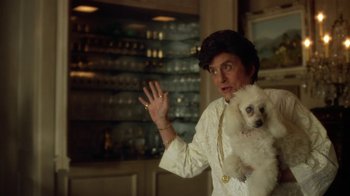 Movie still from “Behind the Candelabra” (2013), directed by Steven Soderbergh – A man holding a white dog in his arms; Medium shot, Over the shoulder angle