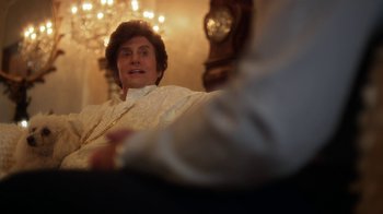 Movie still from “Behind the Candelabra” (2013), directed by Steven Soderbergh – A man sitting on a couch in front of a clock; Close Up shot, Over the shoulder angle