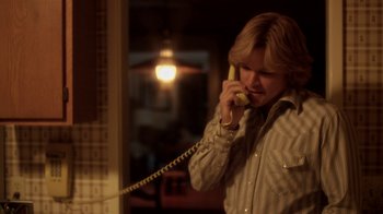 Movie still from “Behind the Candelabra” (2013), directed by Steven Soderbergh – A man talking on a phone while standing next to a window; Medium shot, Low angle