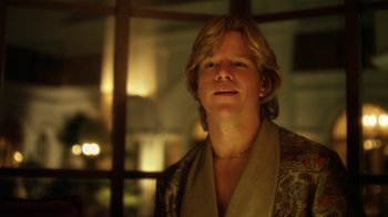 Movie still from “Behind the Candelabra” (2013), directed by Steven Soderbergh – A man with long blonde hair wearing a robe; Close Up shot, Over the shoulder angle