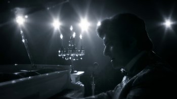 Movie still from “Behind the Candelabra” (2013), directed by Steven Soderbergh – A man sitting in front of a microphone in front of a chandelier; Extreme Close Up shot, Low angle