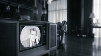 Movie still from “Behind the Candelabra” (2013), directed by Steven Soderbergh – An old tv with a man on it in a living room; Medium shot, High angle