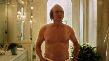 Movie still from “Behind the Candelabra” (2013), directed by Steven Soderbergh – An old man with a shaved head is posing for a picture; Medium shot, Low angle