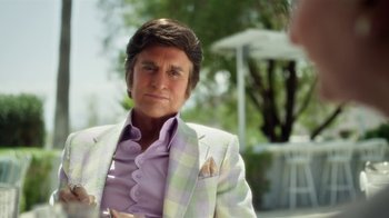 Movie still from “Behind the Candelabra” (2013), directed by Steven Soderbergh – A man wearing a suit and tie sitting in a chair; Close Up shot, Over the shoulder angle