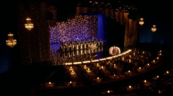 Movie still from “Behind the Candelabra” (2013), directed by Steven Soderbergh – A stage lit up at night with people sitting on the seats; Extreme Wide shot, High angle