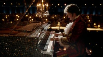Movie still from “Behind the Candelabra” (2013), directed by Steven Soderbergh – A man in a red and gold suit playing a piano; Medium shot, Low angle